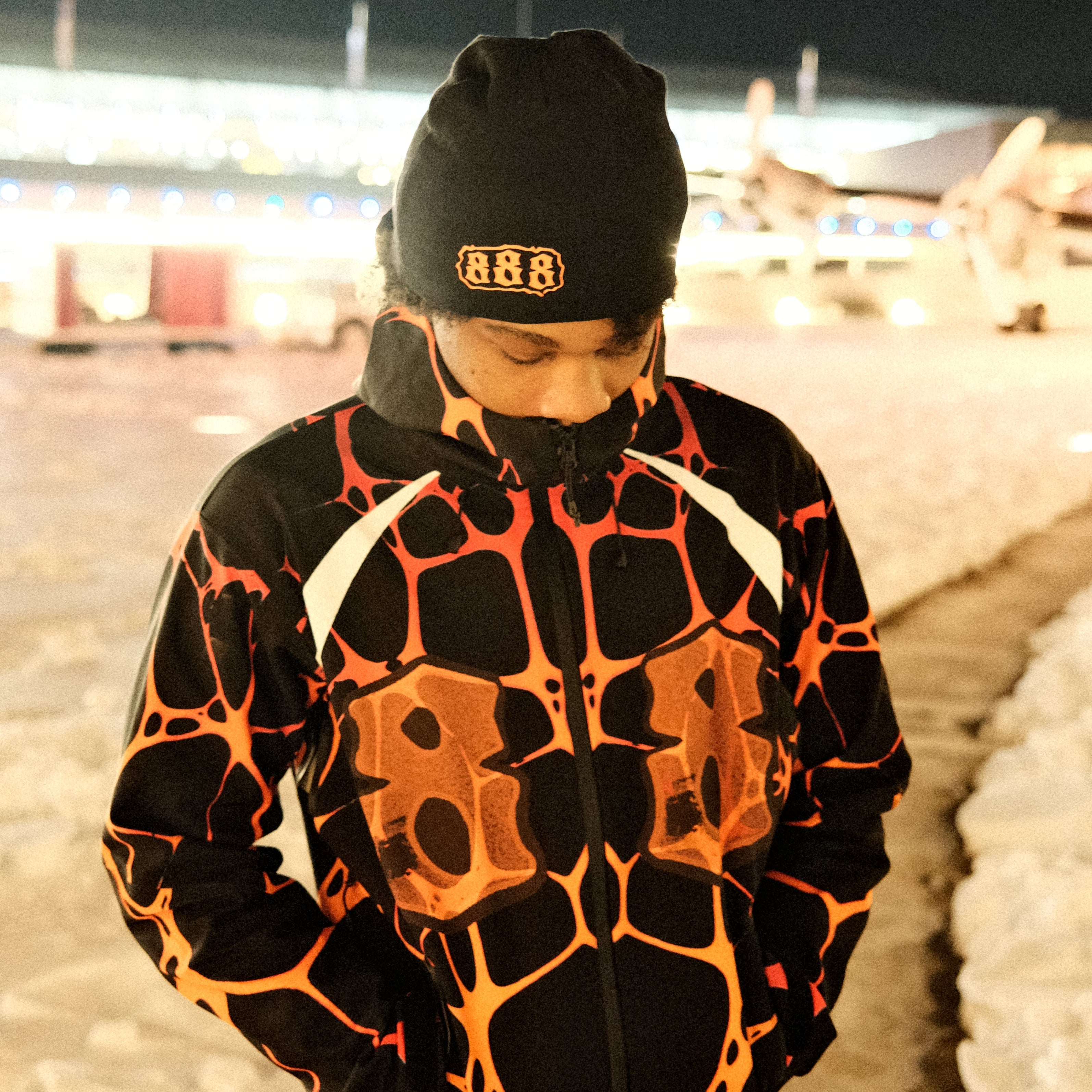 Person wearing a black and orange patterned outfit with a dark background