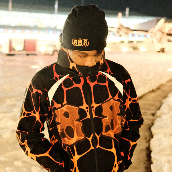 Person wearing a black and orange patterned outfit with a dark background