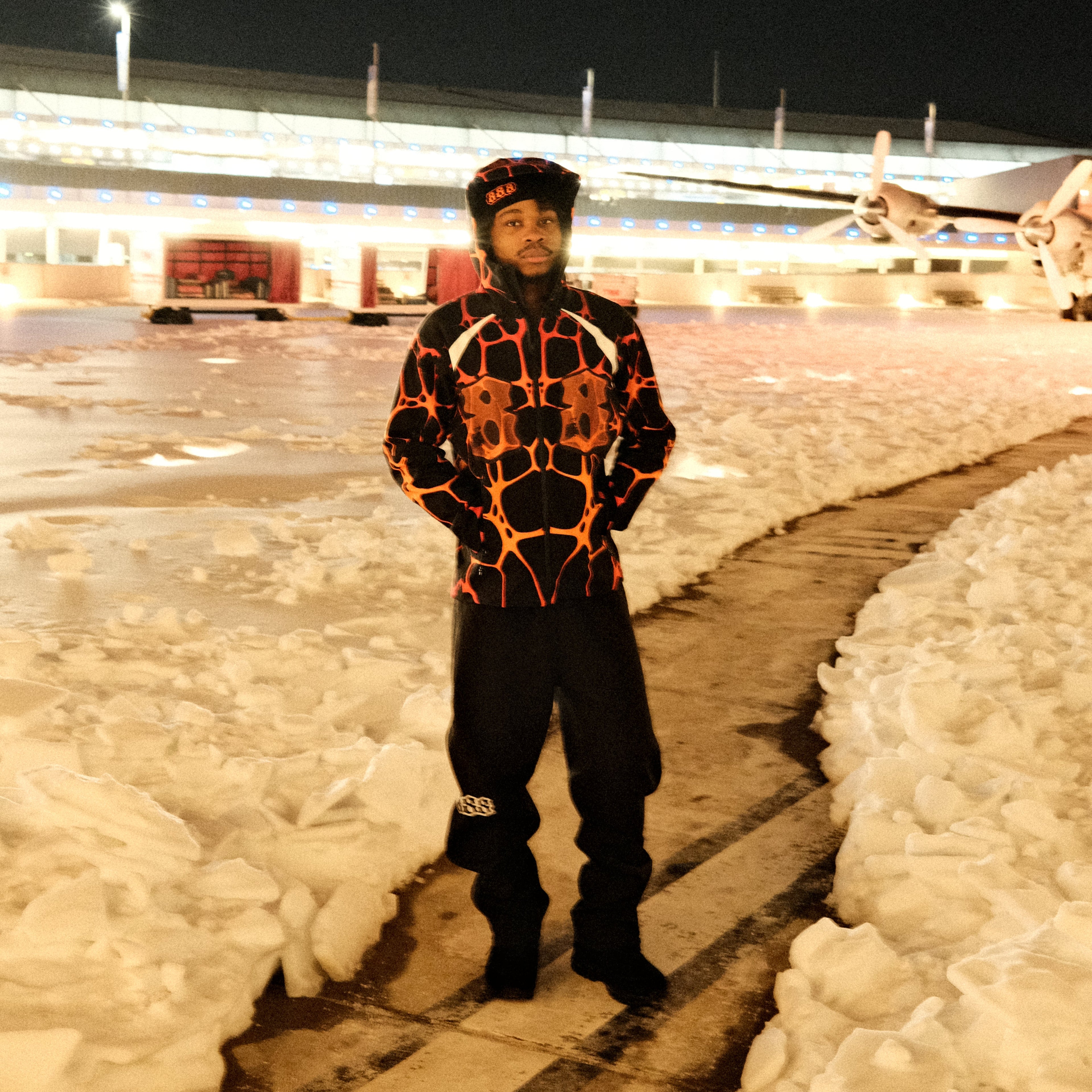 Person wearing a patterned jacket standing on a snowy landscape at night.