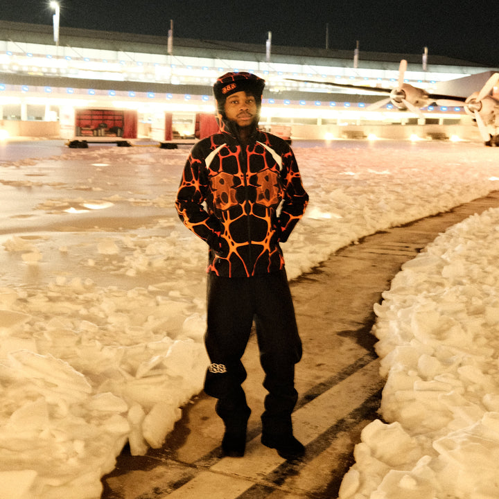 Person wearing a patterned jacket standing on a snowy landscape at night.