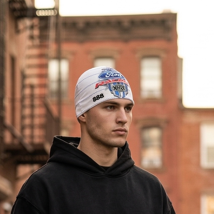 Person wearing a black hoodie and pants standing on a city street with brick buildings in the background.