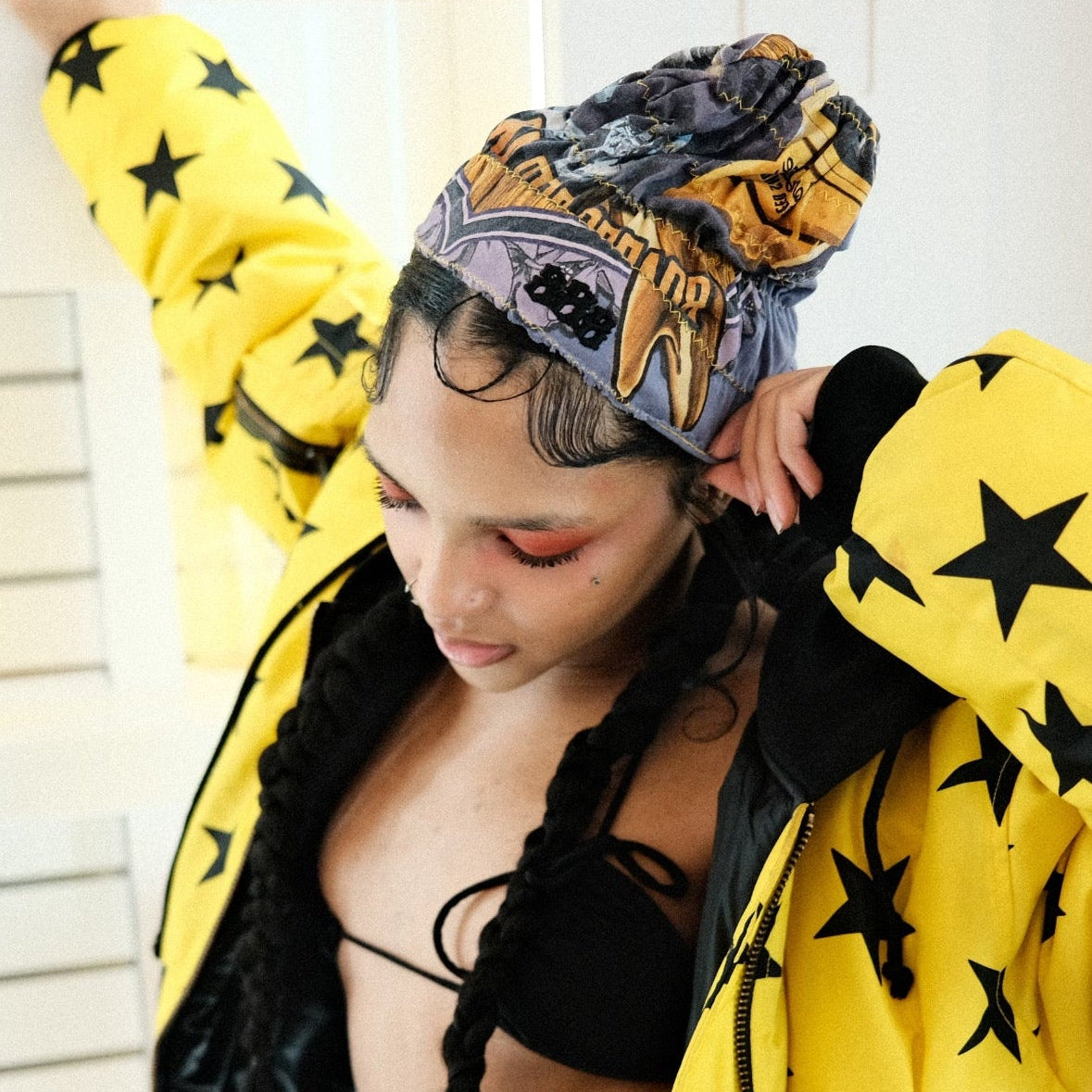 Person wearing a yellow jacket with black star patterns and a headscarf, with a 'Sign Up!' graphic in the corner.